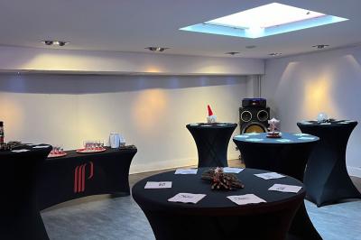 Salle avec un présentoir, des cartons empilés, une table haute décorée et un fond rouge marqué ’50 ans’.