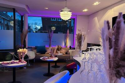 Salle avec un présentoir, des cartons empilés, une table haute décorée et un fond rouge marqué ’50 ans’.