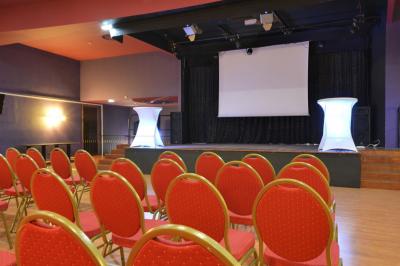 Salle avec un présentoir, des cartons empilés, une table haute décorée et un fond rouge marqué ’50 ans’.