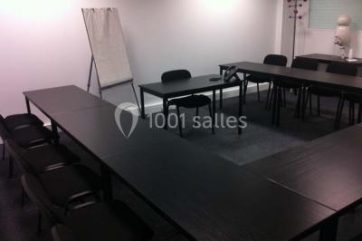 Bureau lumineux avec plusieurs postes de travail équipés de meubles noirs, un ordinateur portable visible au premier plan.