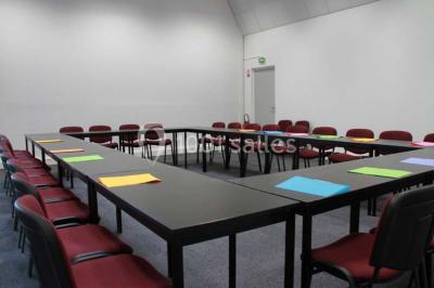 Bureau lumineux avec plusieurs postes de travail équipés de meubles noirs, un ordinateur portable visible au premier plan.