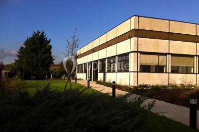 Bureau lumineux avec plusieurs postes de travail équipés de meubles noirs, un ordinateur portable visible au premier plan.