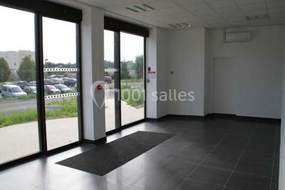 Bureau lumineux avec plusieurs postes de travail équipés de meubles noirs, un ordinateur portable visible au premier plan.