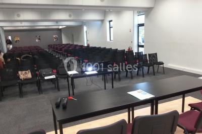 Bureau lumineux avec plusieurs postes de travail équipés de meubles noirs, un ordinateur portable visible au premier plan.