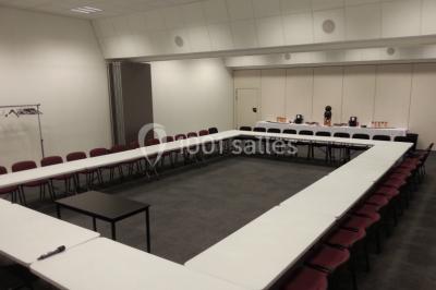 Bureau lumineux avec plusieurs postes de travail équipés de meubles noirs, un ordinateur portable visible au premier plan.