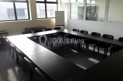 Bureau lumineux avec plusieurs postes de travail équipés de meubles noirs, un ordinateur portable visible au premier plan.