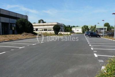 Bureau lumineux avec plusieurs postes de travail équipés de meubles noirs, un ordinateur portable visible au premier plan.
