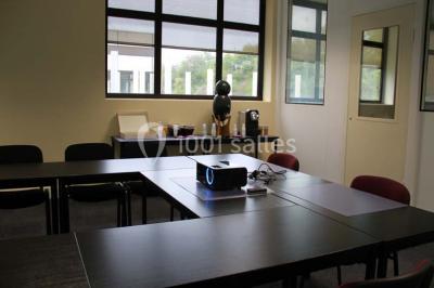 Bureau lumineux avec plusieurs postes de travail équipés de meubles noirs, un ordinateur portable visible au premier plan.