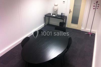 Bureau lumineux avec plusieurs postes de travail équipés de meubles noirs, un ordinateur portable visible au premier plan.