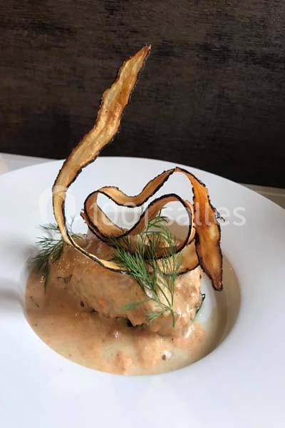 Plat gastronomique composé d'une sauce crémeuse, décoré de chips de légumes et de brins d'aneth.