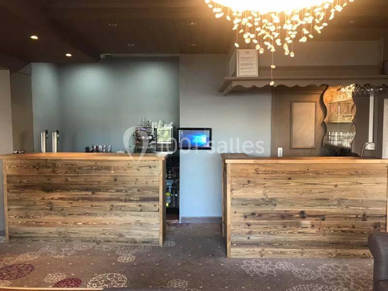 Deux comptoirs en bois dans un hall avec un éclairage suspendu et des équipements visibles à l'arrière-plan.