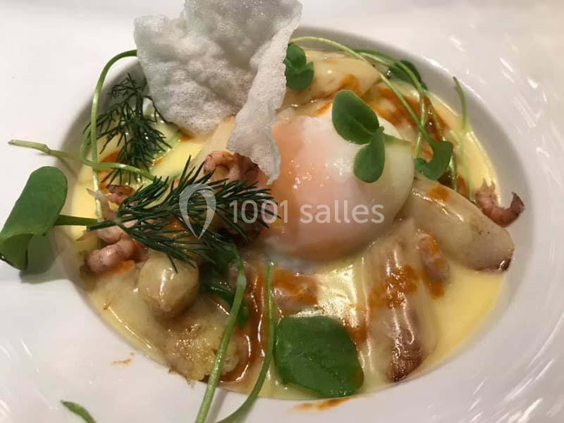 Assiette gastronomique avec œuf poché, asperges, crevettes, herbes fraîches et sauce crémeuse.