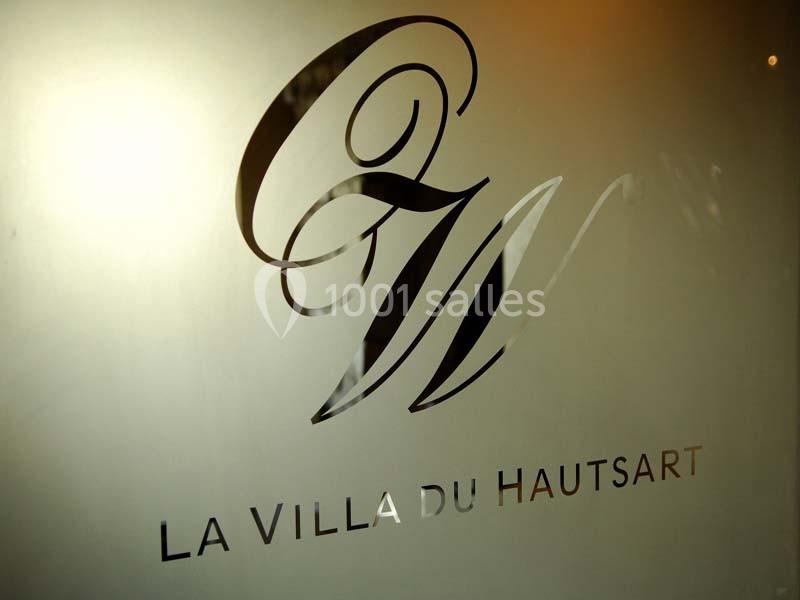 Logo ’La Villa du Hautsart’ avec des initiales stylisées sur une surface en verre dépoli.