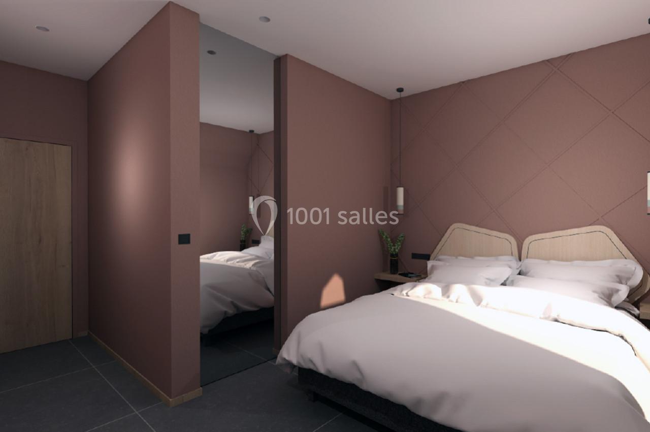 Chambre avec lit double, murs roses, miroir pleine hauteur, éclairage mural et sol en carrelage sombre.