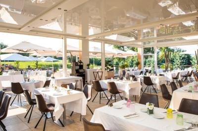 Salle de réception lumineuse avec tables dressées, grandes compositions florales et vue sur une terrasse arborée.