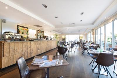 Salle de réception lumineuse avec tables dressées, grandes compositions florales et vue sur une terrasse arborée.