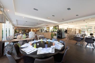 Salle de réception lumineuse avec tables dressées, grandes compositions florales et vue sur une terrasse arborée.