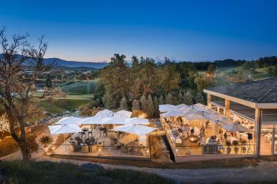 Salle de réception lumineuse avec tables dressées, grandes compositions florales et vue sur une terrasse arborée.