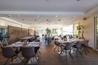 Salle de réception lumineuse avec tables dressées, grandes compositions florales et vue sur une terrasse arborée.