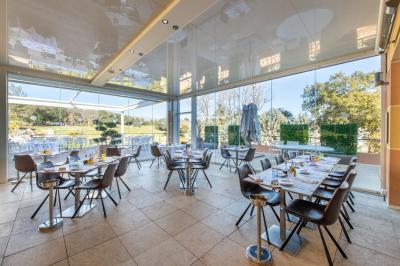 Salle de réception lumineuse avec tables dressées, grandes compositions florales et vue sur une terrasse arborée.