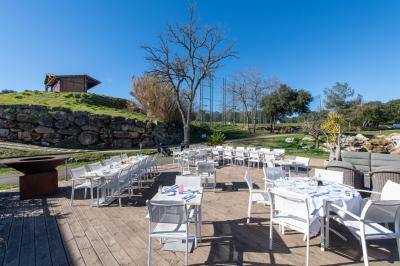 Salle de réception lumineuse avec tables dressées, grandes compositions florales et vue sur une terrasse arborée.