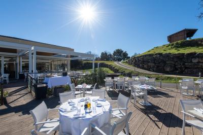 Salle de réception lumineuse avec tables dressées, grandes compositions florales et vue sur une terrasse arborée.