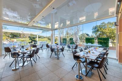 Salle de réception lumineuse avec tables dressées, grandes compositions florales et vue sur une terrasse arborée.
