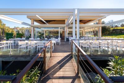 Salle de réception lumineuse avec tables dressées, grandes compositions florales et vue sur une terrasse arborée.