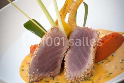 Salle de réception lumineuse avec tables dressées, grandes compositions florales et vue sur une terrasse arborée.