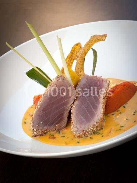 Deux morceaux de thon mi-cuit en croûte de sésame, servis avec une sauce crémeuse et une garniture colorée.