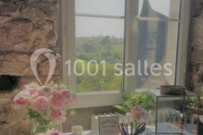 Paysage rural avec des arbres, des collines verdoyantes et une toiture en bois au premier plan sous une lumière douce.