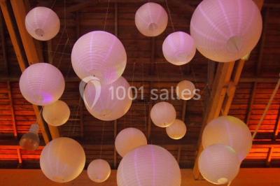 Paysage rural avec des arbres, des collines verdoyantes et une toiture en bois au premier plan sous une lumière douce.