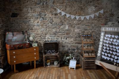 Paysage rural avec des arbres, des collines verdoyantes et une toiture en bois au premier plan sous une lumière douce.
