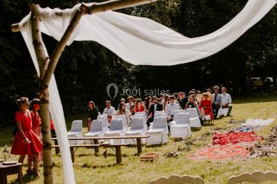 Paysage rural avec des arbres, des collines verdoyantes et une toiture en bois au premier plan sous une lumière douce.