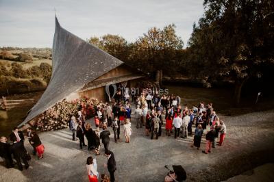 Paysage rural avec des arbres, des collines verdoyantes et une toiture en bois au premier plan sous une lumière douce.
