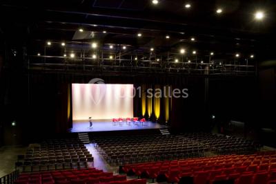 Parking vide devant un bâtiment moderne gris avec l'enseigne ’Le Dastala’ et des arbres en arrière-plan.