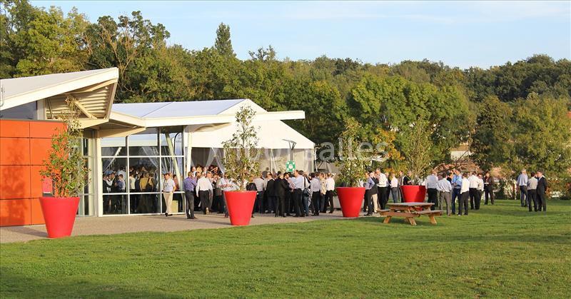 Groupe de personnes rassemblées à l'extérieur près d'un bâtiment moderne entouré de verdure.