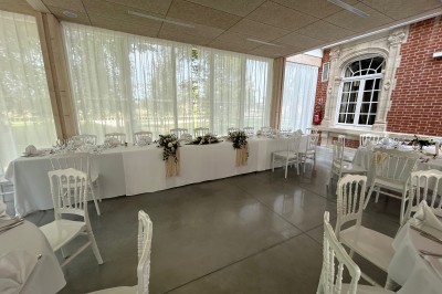 Cérémonie en plein air dans un parc, avec des invités assis face à une mariée et un officiant, devant un manoir.