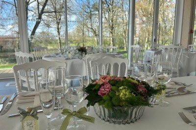Cérémonie en plein air dans un parc, avec des invités assis face à une mariée et un officiant, devant un manoir.