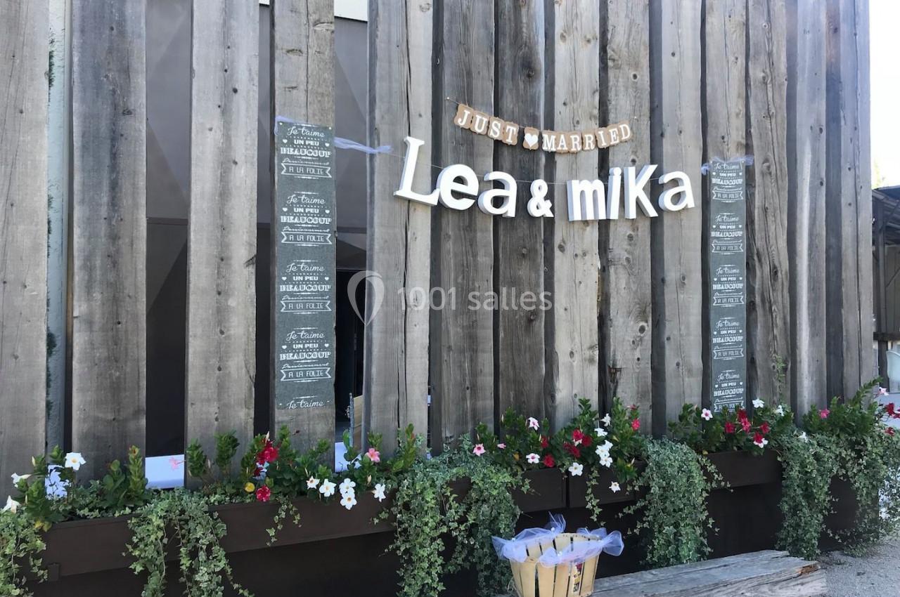 Décoration de mariage avec des panneaux en bois, des fleurs suspendues et une bannière ’Just Married Lea & Mika’.