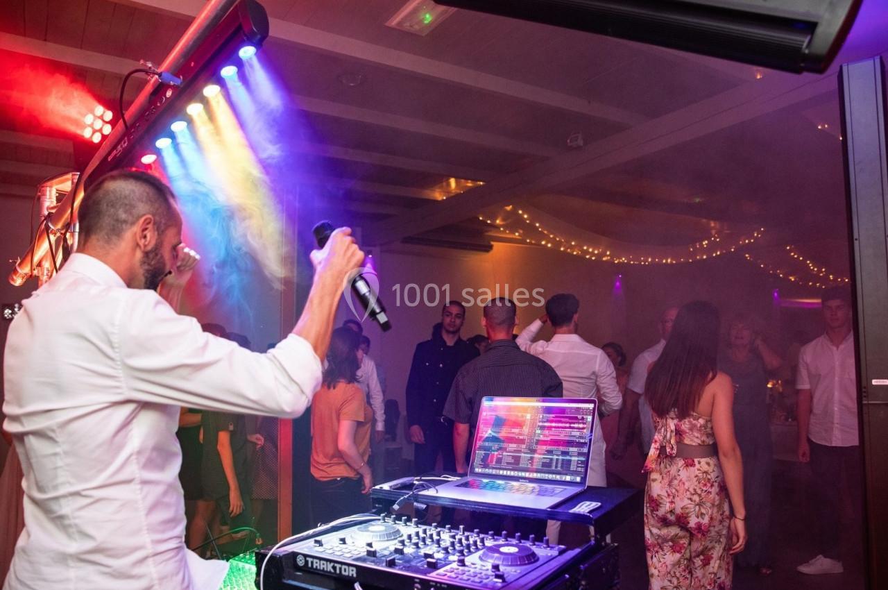 Un DJ anime une soirée dansante avec des lumières colorées et des invités sur la piste de danse.