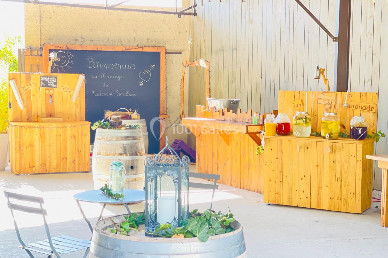 Espace extérieur lumineux avec tables, tonneaux décoratifs et stands en bois proposant boissons artisanales.