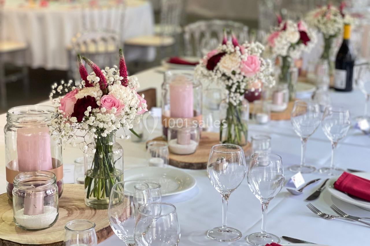 Table décorée pour un événement avec bougies, fleurs blanches et rouges, nappes blanches et serviettes rouges.