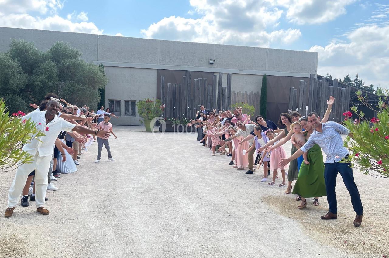 Des personnes alignées en deux rangées forment une haie d'honneur devant un bâtiment sous un ciel partiellement nuageux.