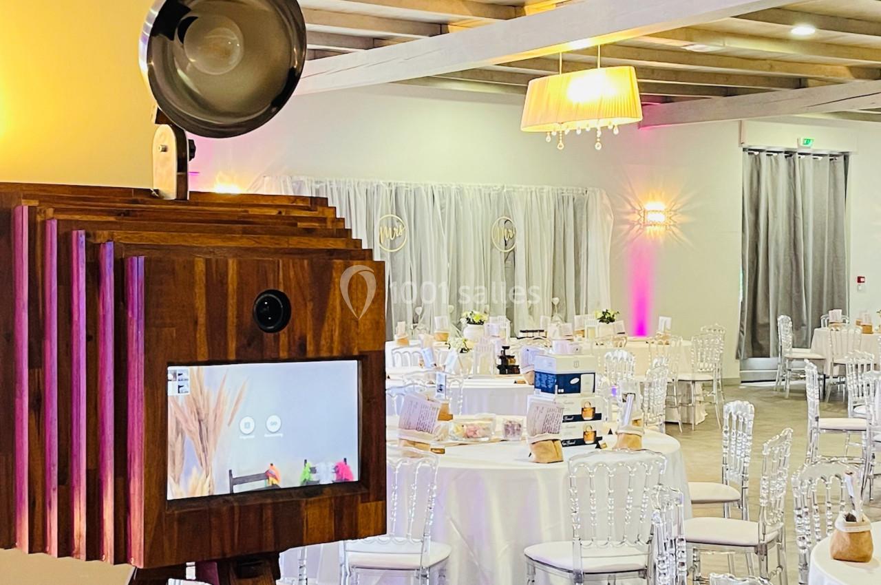 Cabine photo en bois avec écran tactile, installée dans une salle de réception décorée pour un événement.