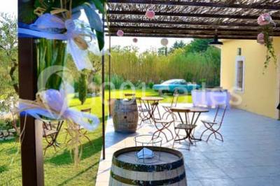 Décoration champêtre avec canapé, fauteuils, bottes de paille et guirlandes dans un jardin verdoyant.