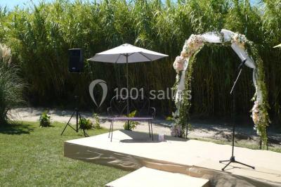 Décoration champêtre avec canapé, fauteuils, bottes de paille et guirlandes dans un jardin verdoyant.