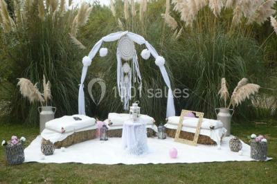 Décoration champêtre avec canapé, fauteuils, bottes de paille et guirlandes dans un jardin verdoyant.