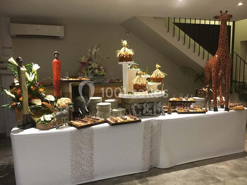 Buffet décoré sur le thème de la savane avec statues, girafe, plats variés et éléments exotiques.