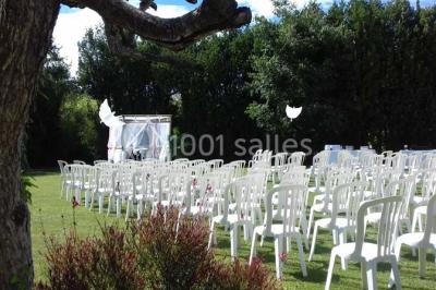 Décoration champêtre avec canapé, fauteuils, bottes de paille et guirlandes dans un jardin verdoyant.